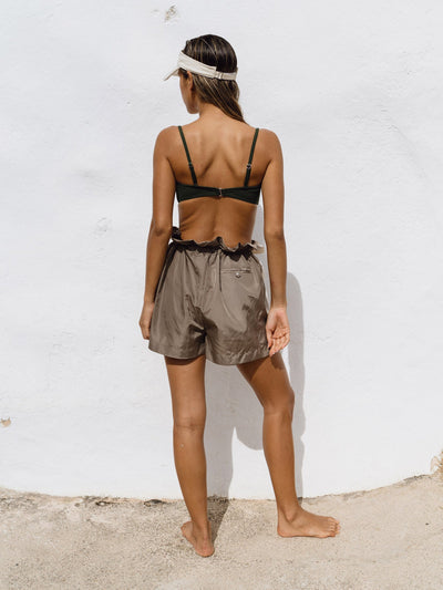 A girl wearing Track Shorts in a sunny environment, paired with a bikini top and sun visor. The shorts, made from comfortable and fast-drying material, feature stylish color-blocking in grey and creme and an oversized fit for versatile activities. The adjustable waist adds both style and comfort.